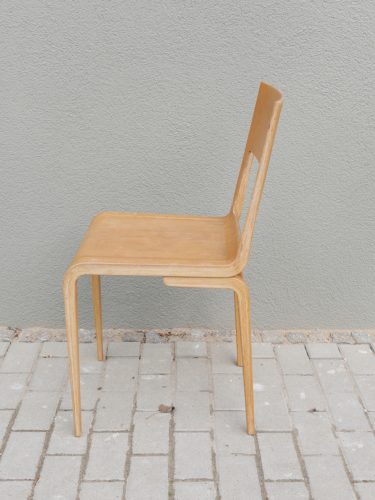 Seitenansicht eines originalen Hellerau-Stuhls der Deutschen Werkstätten Hellerau, Entwurf Erich Menzel, um 1950. Die Aufnahme zeigt das elegante Seitenprofil mit der charakteristischen, aus 29 verleimten Holzlagen gebogenen Konstruktion von Sitzfläche und Rückenlehne sowie die schlanken, leicht nach außen gestellten Beine. Der Stuhl befindet sich in gutem unberührtem Originalzustand und gilt als Designklassiker der DDR-Möbelgeschichte.