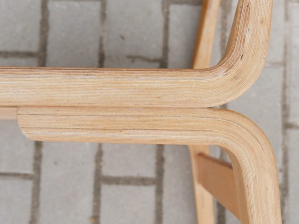 Detailaufnahme des Übergangs von Sitzfläche und Rückenlehne. Die Aufnahme zeigt die formverleimten Holzschichten, die präzise Verarbeitung sowie die elegante Linienführung des Entwurfs von Erich Menzel.
