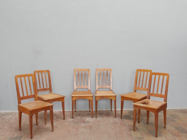 Gruppenansicht des vollständigen sechsteiligen Richard-Riemerschmid-Stuhlsatzes. Die Aufnahme zeigt die harmonische Gestaltung, die charakteristischen senkrechten Rückenstreben sowie die einheitliche originale Ausführung aller sechs Stühle.