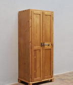 Schmale Seitenansicht des restaurierten historischen Weichholz-Spinds mit originalen Holzverbindungen und gewachster Oberfläche.
