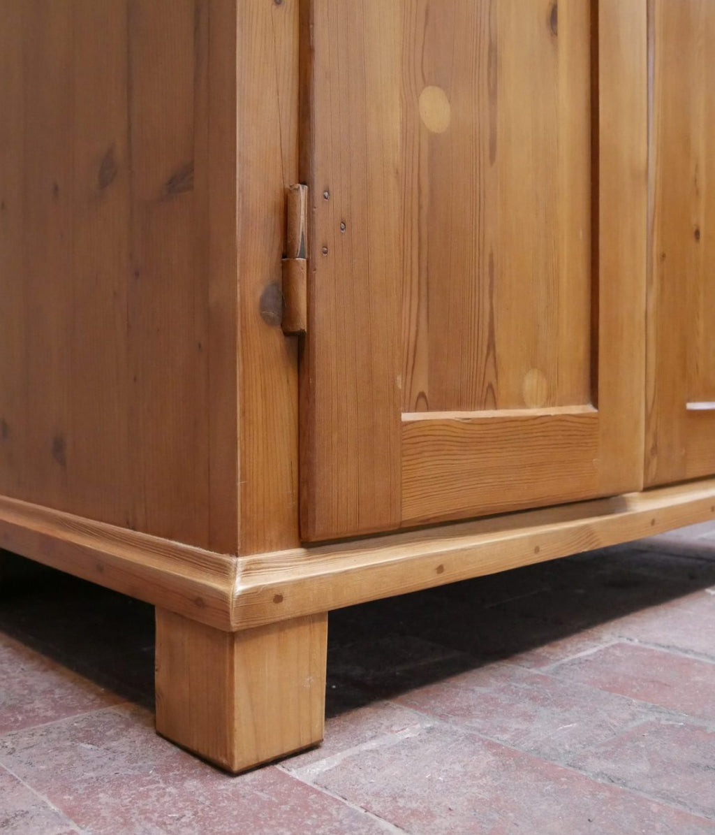 Detailaufnahme des Sockelbereichs des historischen Weichholz-Spinds mit massiver Holzkonstruktion und restaurierter Oberfläche.