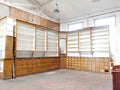 Vollständige historische Apotheken- beziehungsweise Drogerieeinrichtung aus der Zeit um 1900–1910 in originalem Zustand. Die raumhohe Ladeneinrichtung aus massiver Kiefer mit offenen Regalen, zahlreichen Schubladen und eleganten Jugendstil-Elementen ist in einer Gesamtansicht zu sehen.