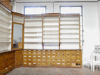 Frontansicht der raumhohen Apothekeneinrichtung mit durchgehenden offenen Regalen, originalen Unterschränken und klassischer Jugendstil-Gestaltung aus einer historischen Apotheke oder Drogerie.