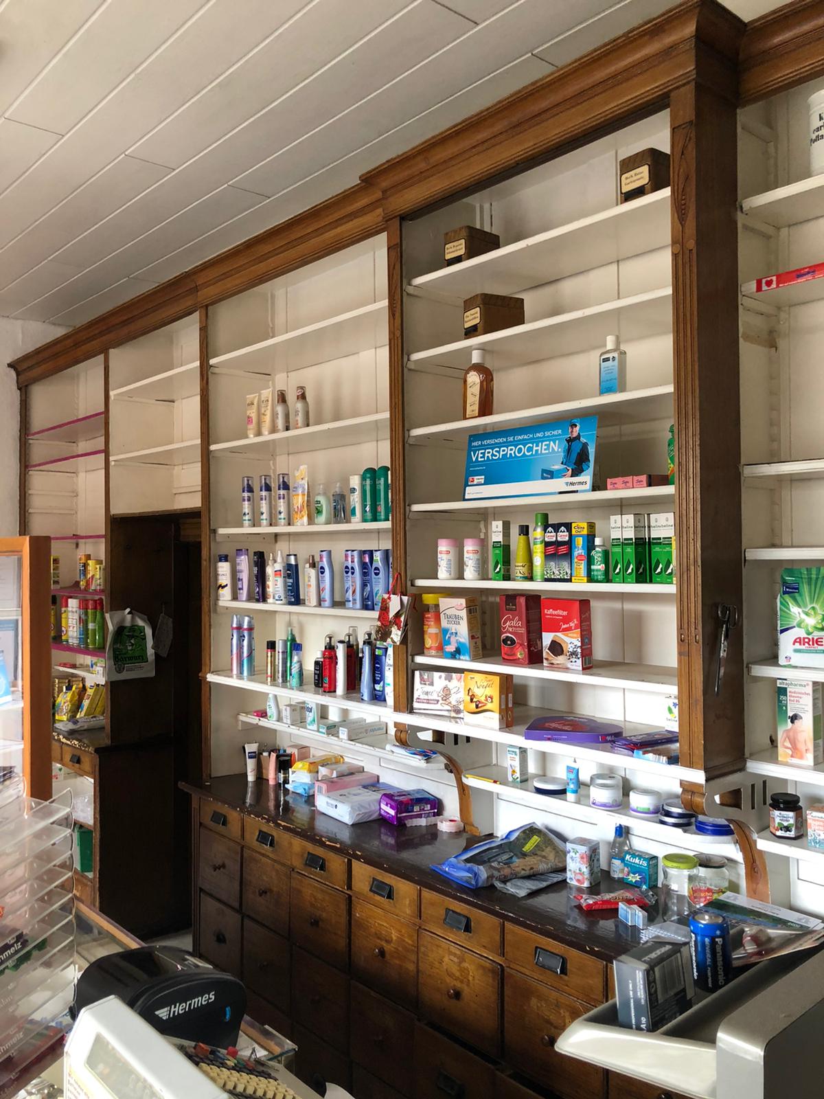 Historische Apothekeneinrichtung im aufgebauten Zustand mit eingeräumten Regalen. Die Aufnahme zeigt die originale Nutzung als Verkaufs- und Präsentationseinrichtung in einer Apotheke oder Drogerie.