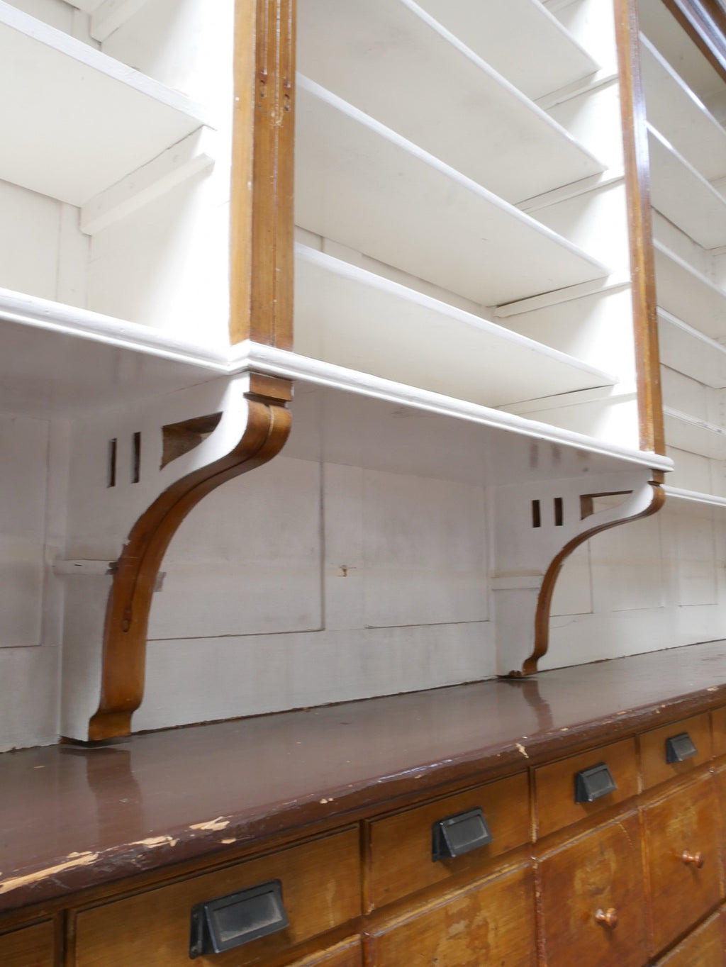 Nahaufnahme einer originalen Jugendstil-Konsole unter den Regalböden. Sichtbar sind die geschwungene Form und die hochwertige handwerkliche Verarbeitung des historischen Möbelstücks.