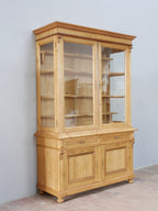 Schräg fotografierte Frontansicht der restaurierten Bibliotheksvitrine. Die Aufnahme zeigt die hochwertige Verarbeitung, die dreiseitige Verglasung sowie die charakteristischen Proportionen des seltenen Möbelstücks aus der Gründerzeit.