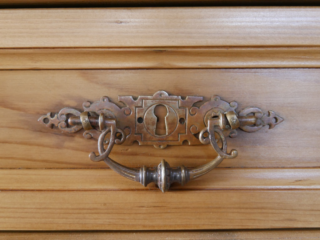 Detailaufnahme eines originalen historischen Möbelbeschlags mit kunstvoll gearbeitetem Griff. Die fein gearbeiteten Metallbeschläge unterstreichen den authentischen Charakter der Bibliotheksvitrine von etwa 1890.