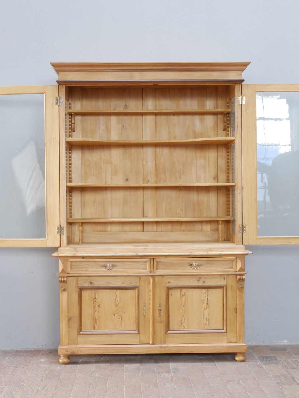 Bibliotheksvitrine mit geöffnetem Oberteil und sichtbaren Einlegeböden. Die Aufnahme verdeutlicht den großzügigen Stauraum und die höhenverstellbaren Regalböden des ehemaligen Ladenschranks.