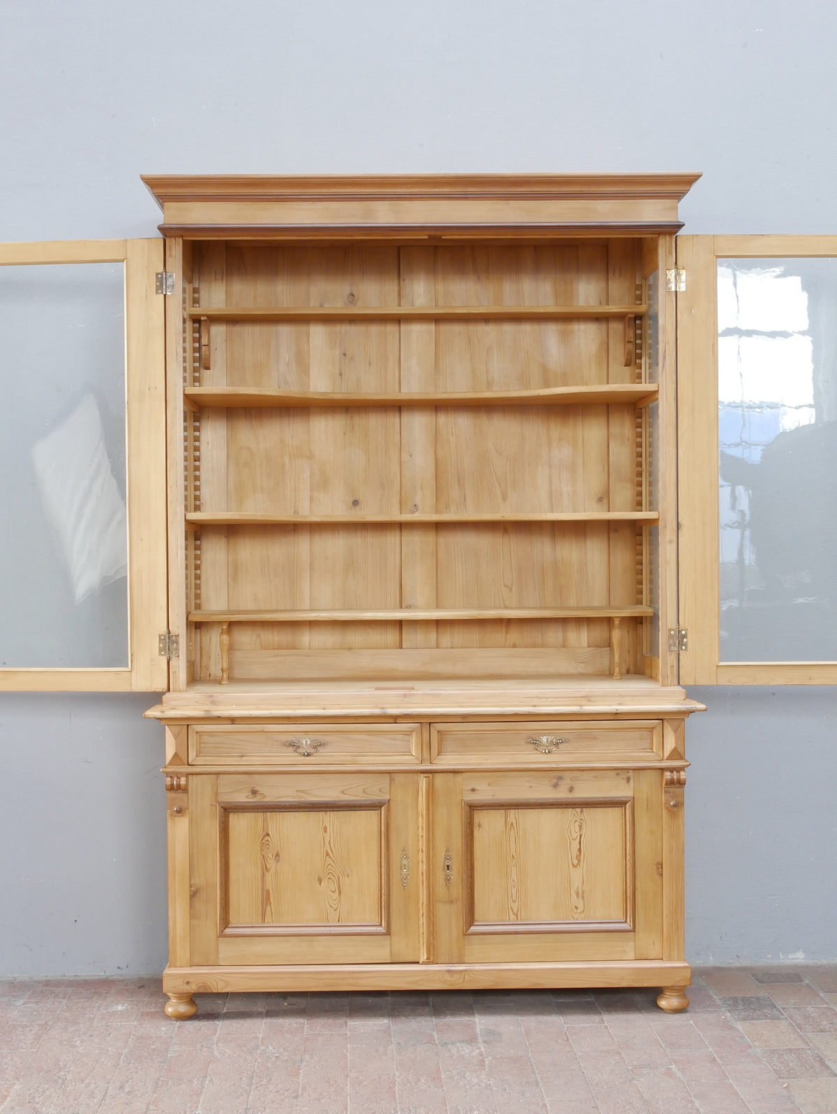 Bibliotheksvitrine mit geöffnetem Oberteil und sichtbaren Einlegeböden. Die Aufnahme verdeutlicht den großzügigen Stauraum und die höhenverstellbaren Regalböden des ehemaligen Ladenschranks.
