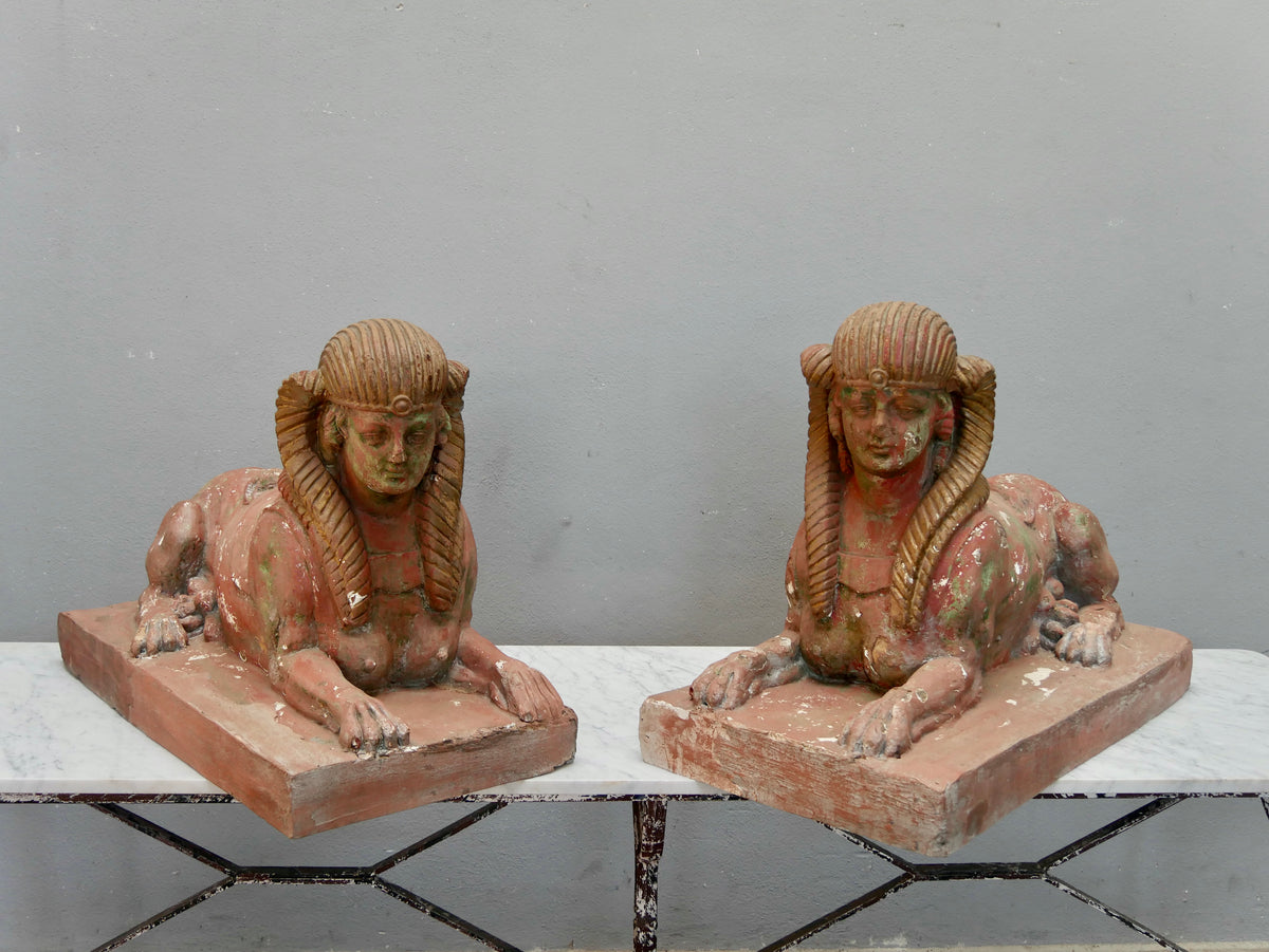 Frontansicht des antiken Sphingenpaares mit beiden Figuren nebeneinander. Gut erkennbar sind die weiblichen Köpfe mit Nemes-Kopftuch, die liegenden Löwenkörper sowie die historische Farbpatina der Terrakottafiguren.
