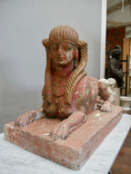 Seitenansicht einer antiken Sphinx aus Terrakotta. Die Aufnahme zeigt den liegenden Löwenkörper, den rechteckigen Sockel sowie die authentischen Alters- und Gebrauchsspuren der historischen Skulptur.