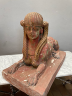 Schräg aufgenommene Frontansicht einer antiken Sphinx. Die Skulptur zeigt den weiblichen Kopf, den liegenden Löwenkörper sowie den massiven Sockel mit schöner historischer Patina.
