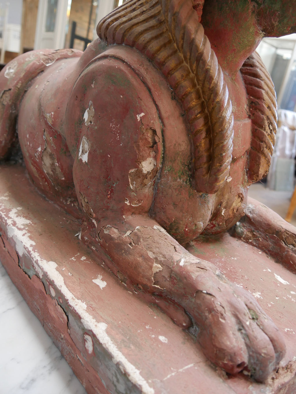 Nahaufnahme des seitlichen Löwenkörpers einer antiken Sphinx. Sichtbar sind die modellierten Rundungen, die originale Oberfläche und die historischen Gebrauchsspuren des Materials.