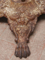 Detailaufnahme einer kunstvoll ausgearbeiteten Löwentatze am Gusseisenfuß des Gartentischs. Die Aufnahme zeigt die hochwertige Gussarbeit sowie die originale Patina mit erhaltenen Farbresten.