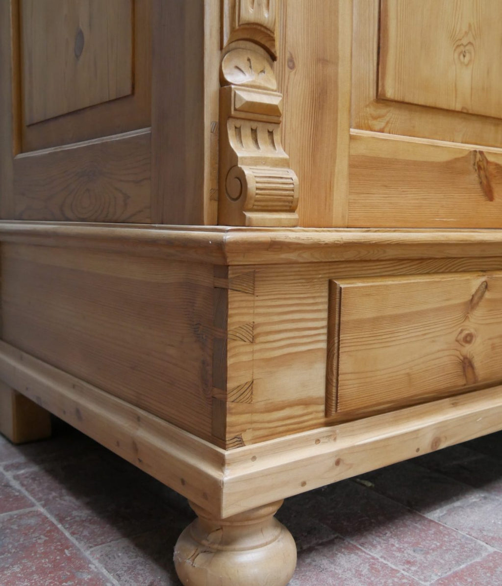 Detailaufnahme der unteren Sockelecke mit profilierter Zierleiste und Kugelfuß. Die Aufnahme zeigt die solide handwerkliche Verarbeitung und die elegante Linienführung des historischen Schranks.