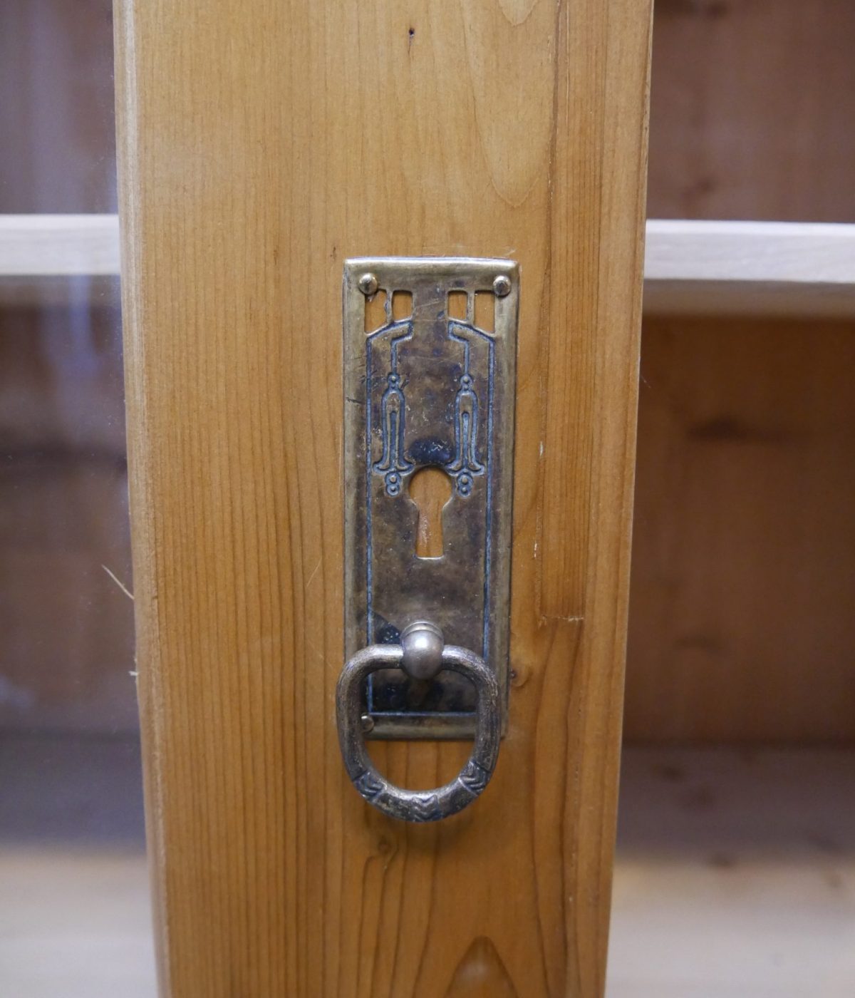 Nahaufnahme des originalen Schlosses beziehungsweise Beschlags an der Tür des antiken Lehrmittelschranks. Das historische Metallbeschlag-Detail unterstreicht den authentischen Charakter des Möbels.