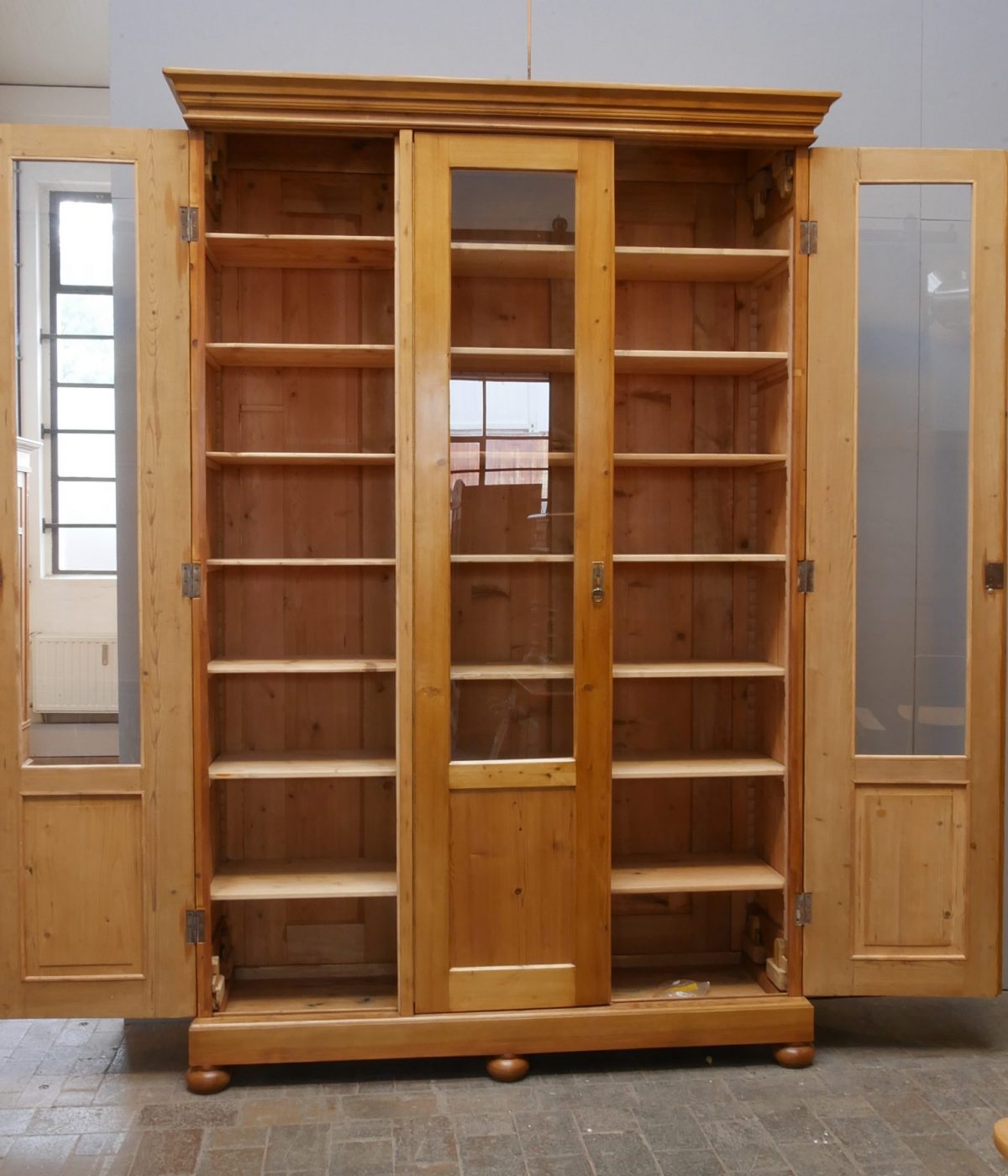 Antiker Lehrmittelschrank mit geöffneten Türen und vollständig sichtbaren Regalböden. Die Aufnahme zeigt den großzügigen Stauraum und die verstellbaren Einlegeböden des historischen Vitrinenschranks.