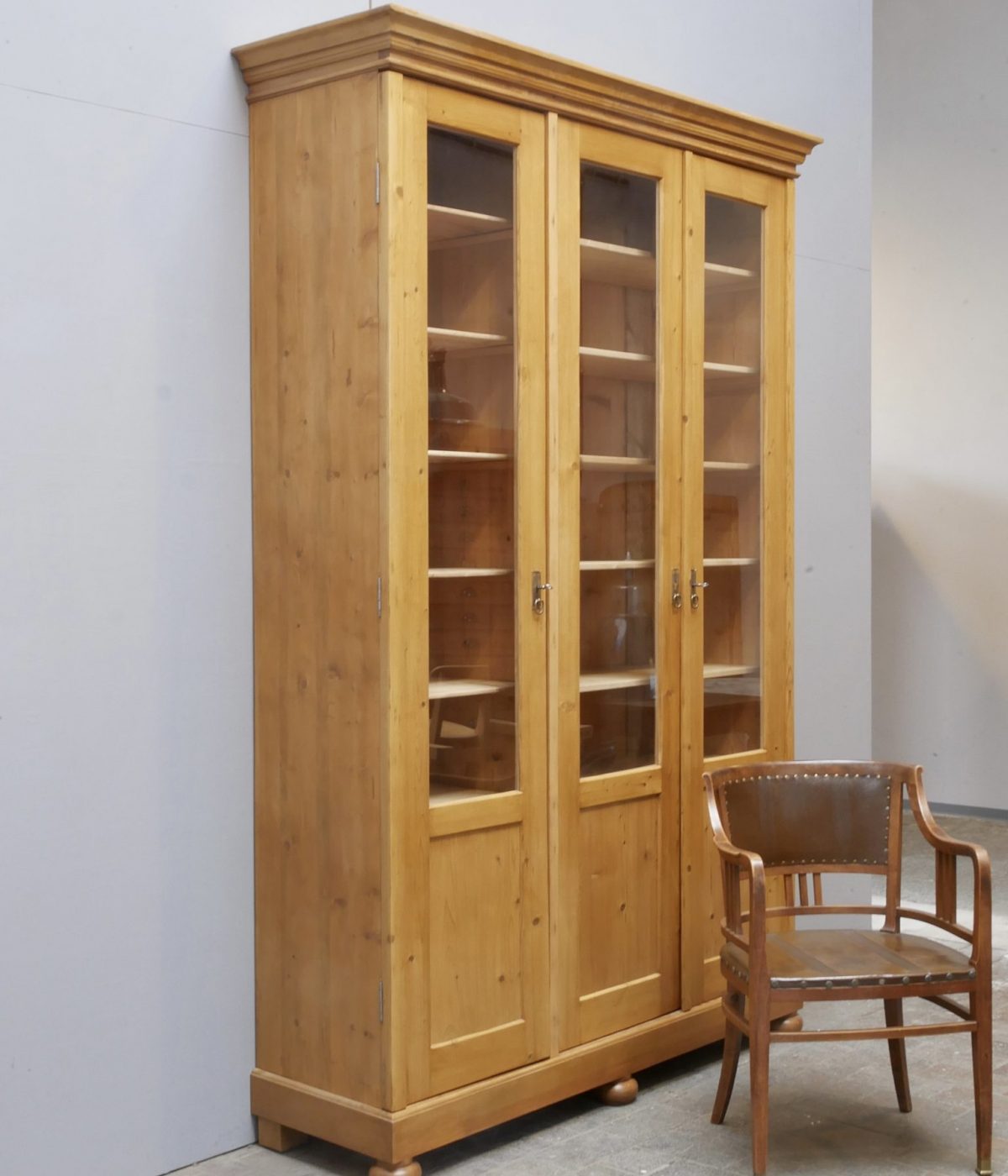 Originaler Lehrmittelschrank aus Weichholz von etwa 1910 in restauriertem Zustand. Die große zweitürige Vitrine mit verglasten Türen, verstellbaren Einlegeböden und schöner Kranzleiste zeigt die komplette Frontansicht des historischen Schranks.