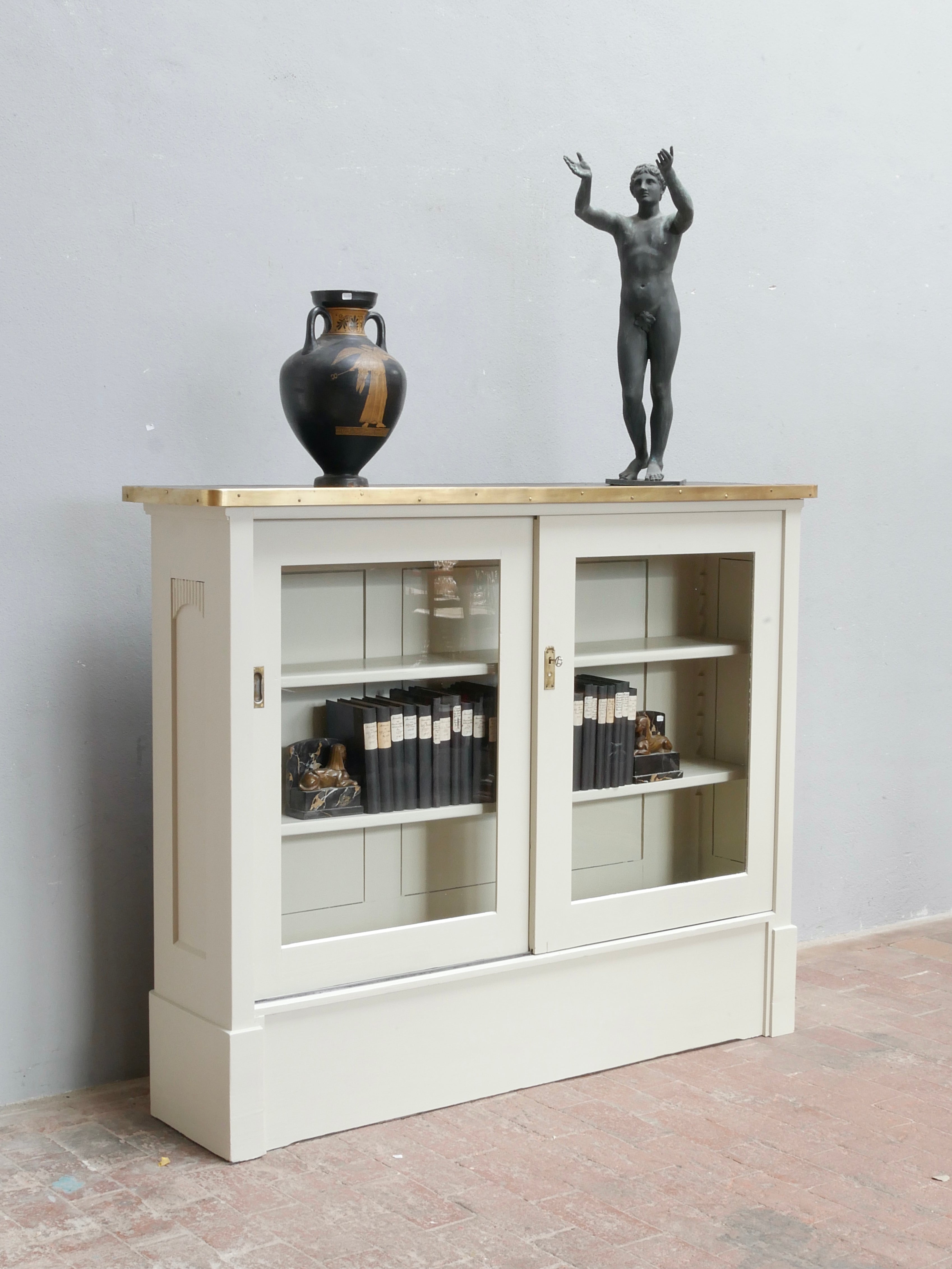 Weißer Vitrinenschrank mit Glastüren als stilvoller Barschrank oder Sideboard dekoriert mit Wohnaccessoires