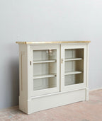 Weißes Highboard mit zwei Glastüren und offenen Einlegeböden in schräger Vorderansicht