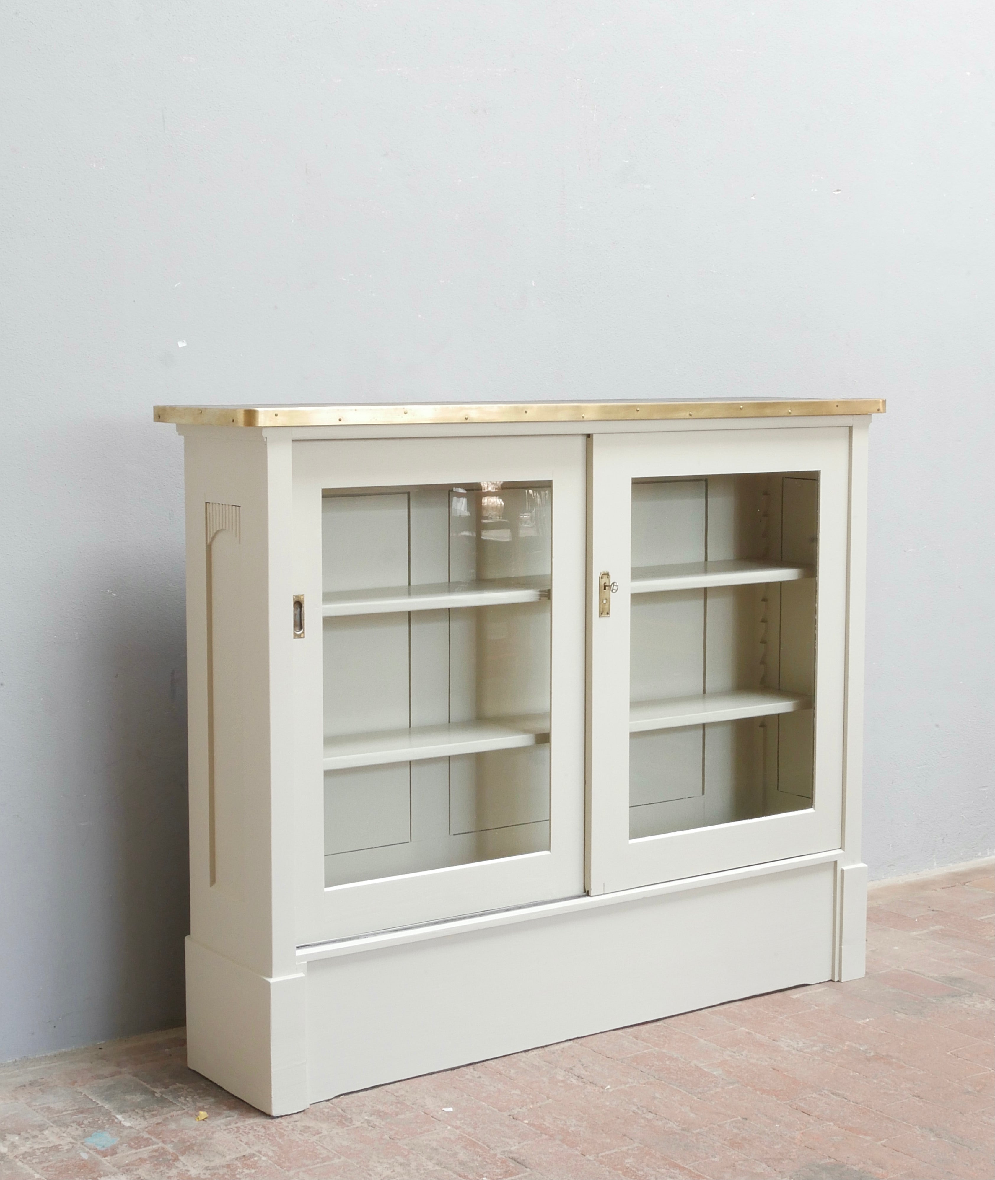 Weißes Highboard mit zwei Glastüren und offenen Einlegeböden in schräger Vorderansicht