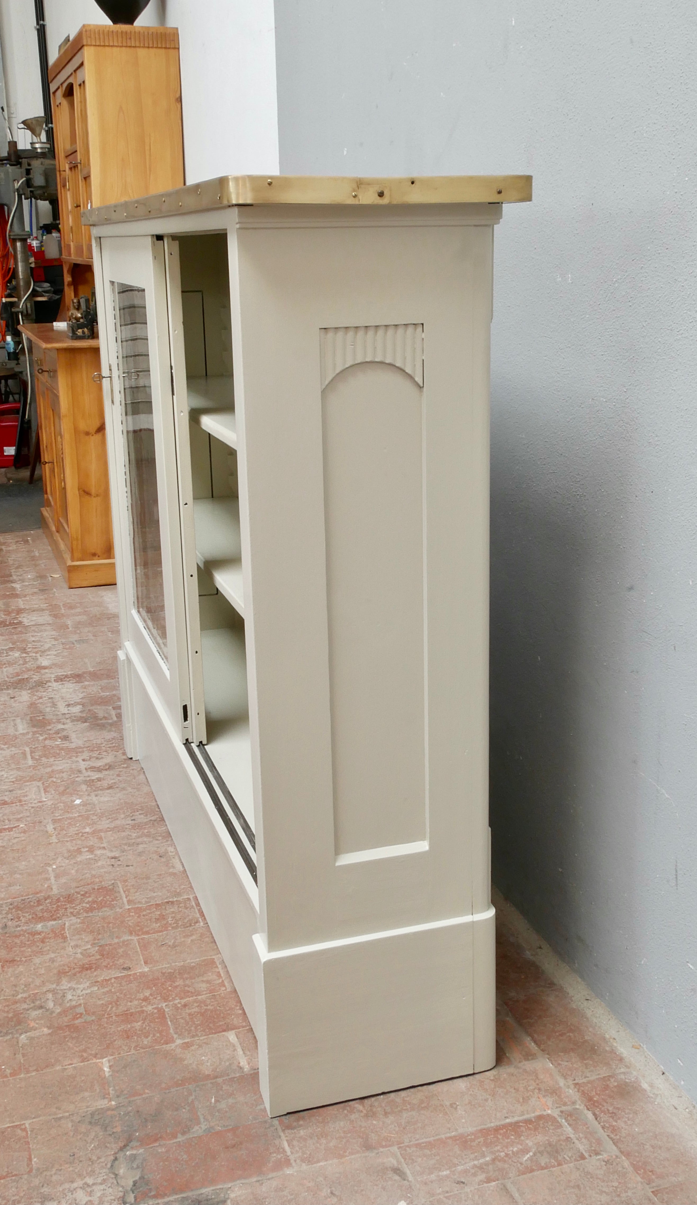 Detailansicht der geöffneten Seitentür des weißen Highboards mit Rahmenprofil.