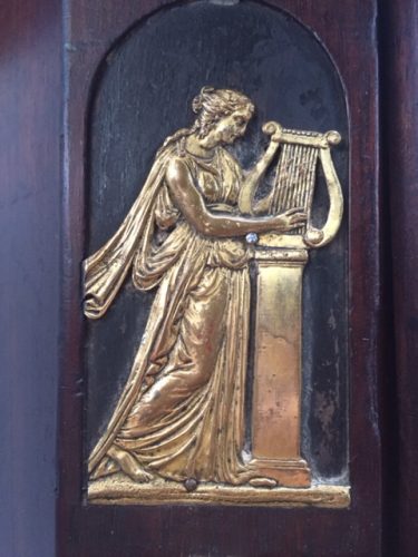 Detailaufnahme eines weiteren originalen feuervergoldeten Bronzebeschlags mit klassischer Figuren-Darstellung. Die kunstvolle Ausarbeitung macht diesen Beschlag zu einem besonderen Blickfang der Empire-Kommode.