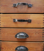 Detailansicht der Holzschubladen mit unterschiedlichen historischen Metallgriffen des KR34 Schranks
