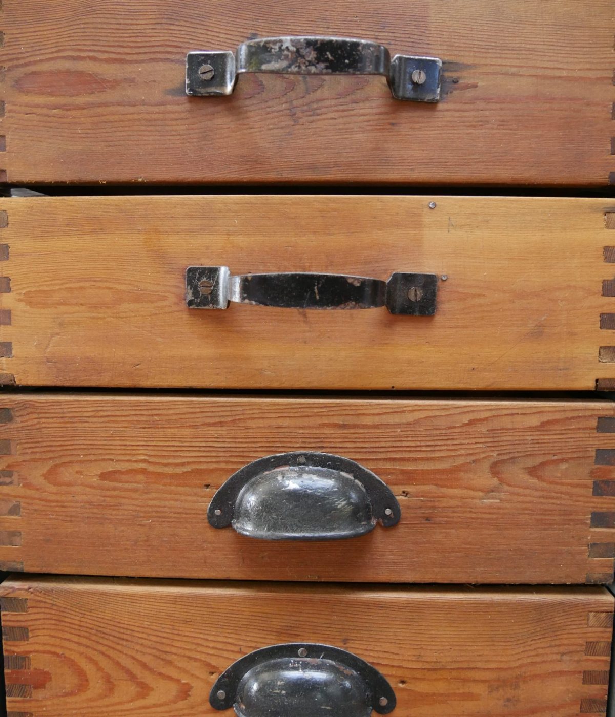 Detailansicht der Holzschubladen mit unterschiedlichen historischen Metallgriffen des KR34 Schranks