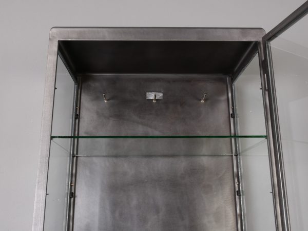 Detailaufnahme des oberen Innenraums des restaurierten Vitrinenschrankes. Die stabilen Glas-Einlegeböden, die saubere Restaurierung und die mehrfach höhenverstellbaren Bodenträger verdeutlichen die hochwertige Verarbeitung des historischen Industrieschrankes.
