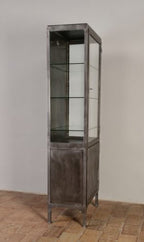 Seitenansicht des antiken Arzt- und Vitrinenschrankes aus der Zeit um 1910–1920. Die schlanke Bauform, der verglaste Oberteil und der geschlossene Unterschrank verdeutlichen die elegante industrielle Konstruktion und die vielseitige Einsetzbarkeit als Praxis-, Büro- oder Sammlerschrank.
