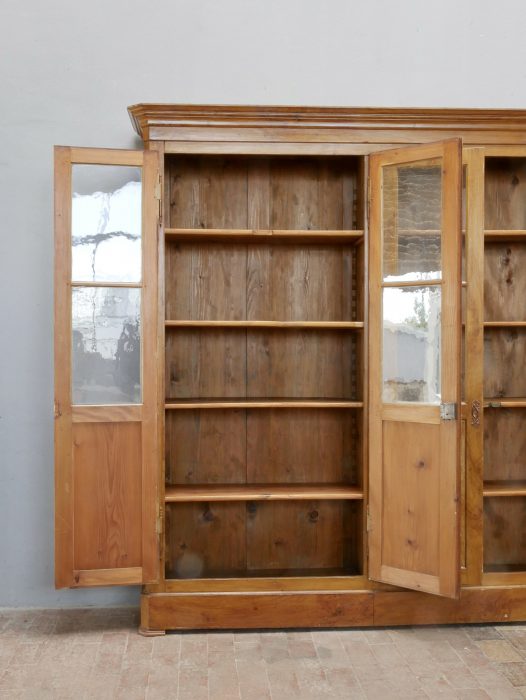 Frontalaufnahme des vollständig geöffneten Biedermeier Bibliotheksschranks. Die originale Innenausstattung mit den großzügigen Regalfächern und den verglasten Türen zeigt die hochwertige Verarbeitung und Funktionalität.
