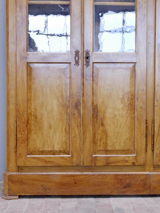 Detailaufnahme der oberen Türpartie mit den originalen Glasscheiben und der historischen Bierlasur. Die gleichmäßige Maserung und die hochwertige Verarbeitung unterstreichen die Qualität des Möbelstücks.