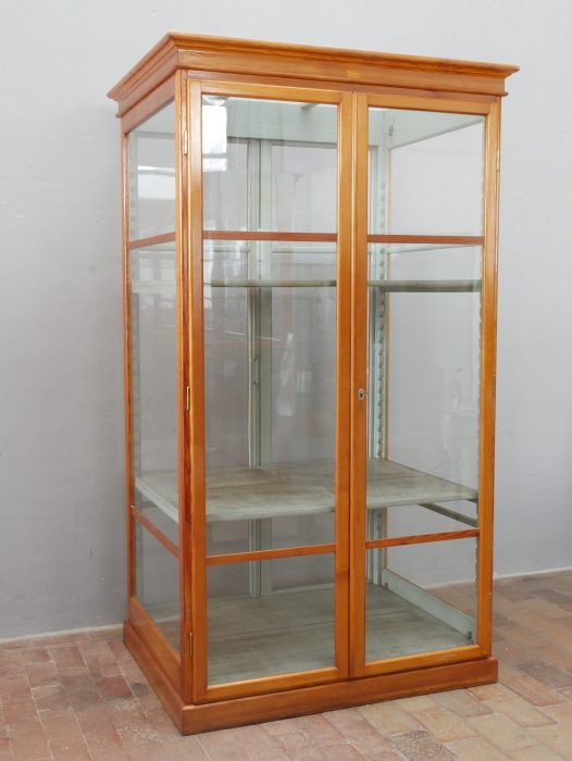 Frontansicht der originalen Vitrine mit feinen Holzprofilen, großflächiger Verglasung und oberem Gesims. Die Aufnahme zeigt die harmonischen Proportionen und den sehr guten Originalzustand.