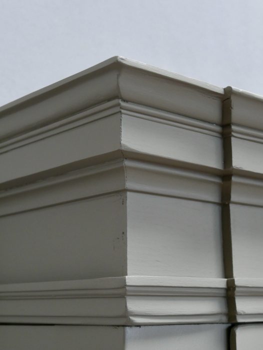 Nahaufnahme der kräftig profilierten Empire-Kranzleiste. Die architektonische Gestaltung und die hochwertige handwerkliche Verarbeitung des Schranks werden hervorgehoben.