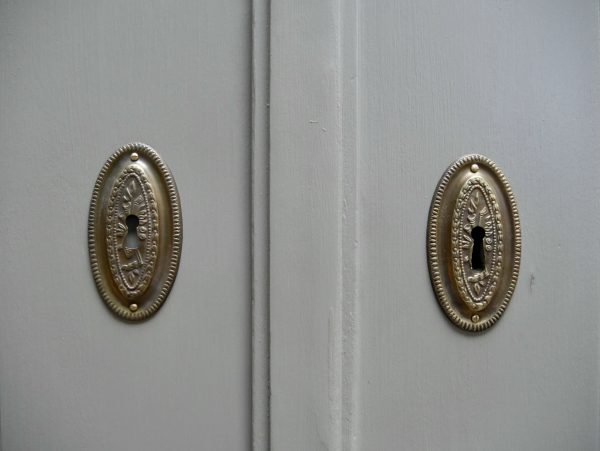 Detailaufnahme des großen originalen Türschlosses mit historischen Schlüsselschildern an den beiden Schranktüren.
