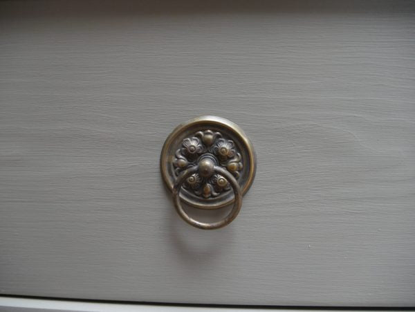 Detailaufnahme des originalen Schubladenknopfes aus Metall an einer der unteren Schubladen. Die historische Ausführung und die schöne altersbedingte Patina sind gut erkennbar.