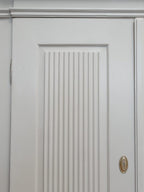 Detailaufnahme einer Tür mit den charakteristischen großen Kannelierungen und der aufwendig gearbeiteten Türfüllung des Empire Kleiderschranks.