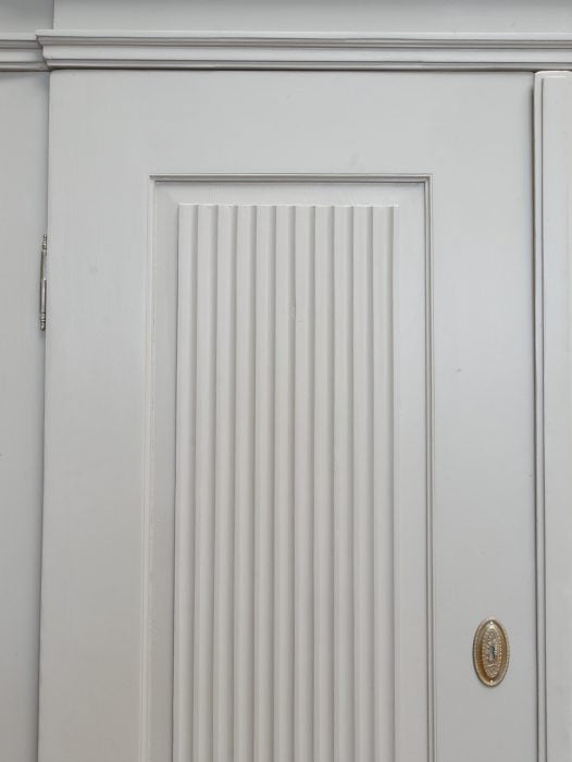 Detailaufnahme einer Tür mit den charakteristischen großen Kannelierungen und der aufwendig gearbeiteten Türfüllung des Empire Kleiderschranks.