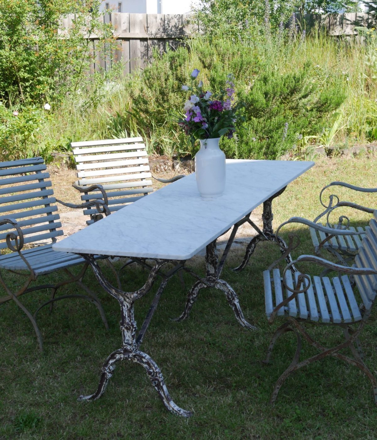 Schrägansicht des französischen Gartentischs mit rechteckiger Marmorplatte und dekorativem Eisengestell.