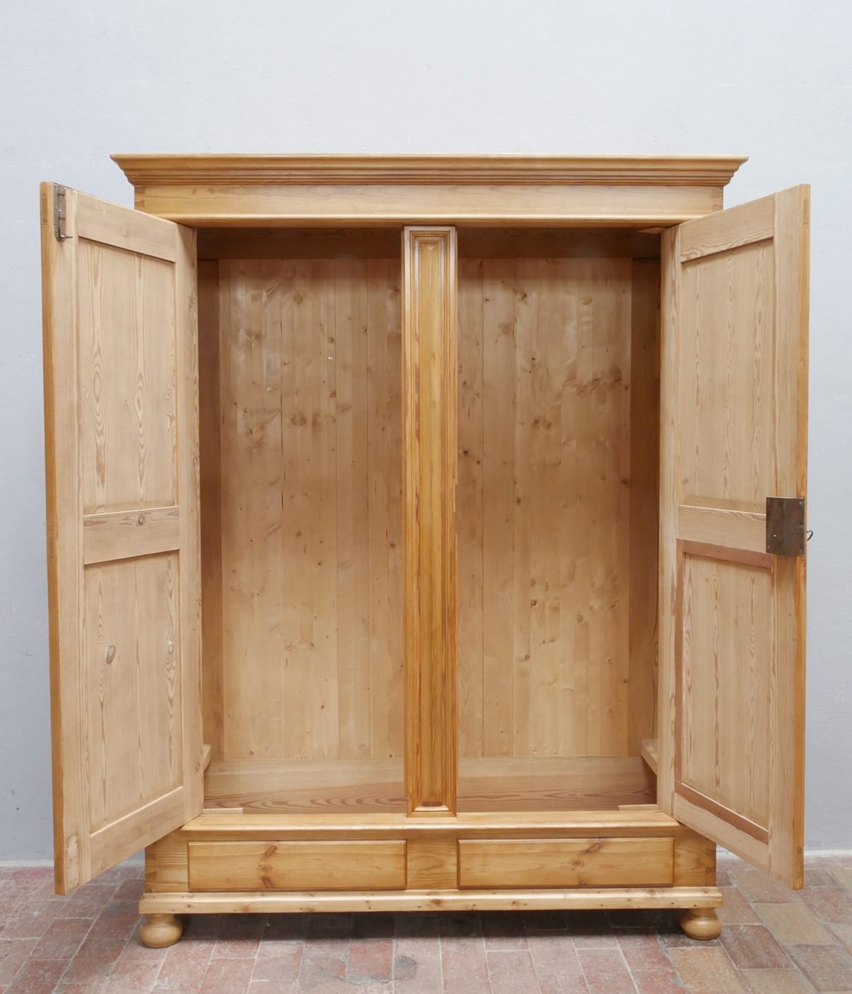 Geöffneter Gründerzeit Kleider- und Wäscheschrank mit großzügigem Innenraum und Kleiderstange. Die Aufnahme zeigt den geräumigen Stauraum sowie die hochwertige Verarbeitung des historischen Schranks.