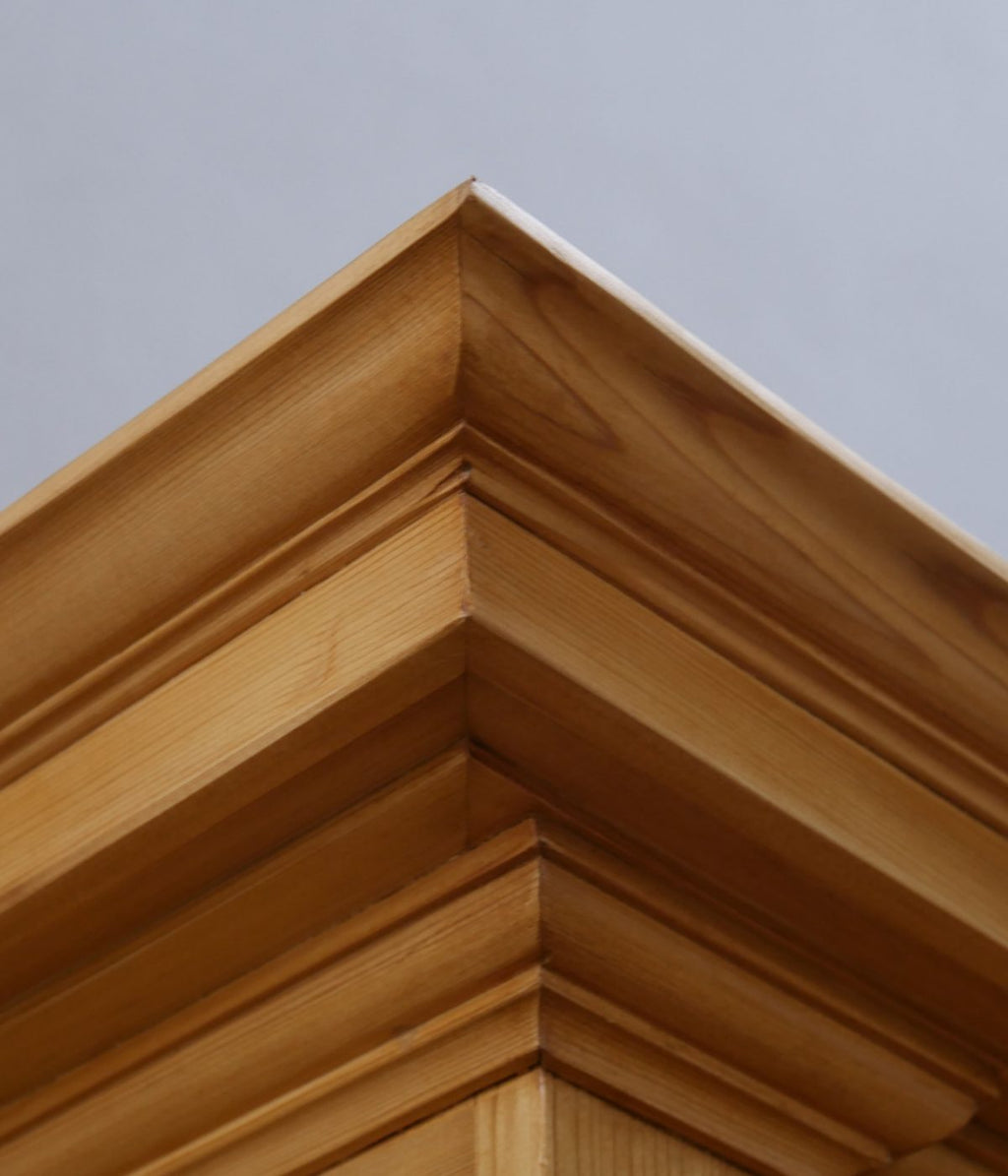 Detailaufnahme der mehrfach getreppten Kranzleiste an einer Schrankecke. Die aufwendige Profilierung und die natürliche Holzmaserung zeigen die exzellente Schreinerarbeit der Gründerzeit.