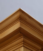 Detailaufnahme der mehrfach getreppten Kranzleiste an einer Schrankecke. Die aufwendige Profilierung und die natürliche Holzmaserung zeigen die exzellente Schreinerarbeit der Gründerzeit.