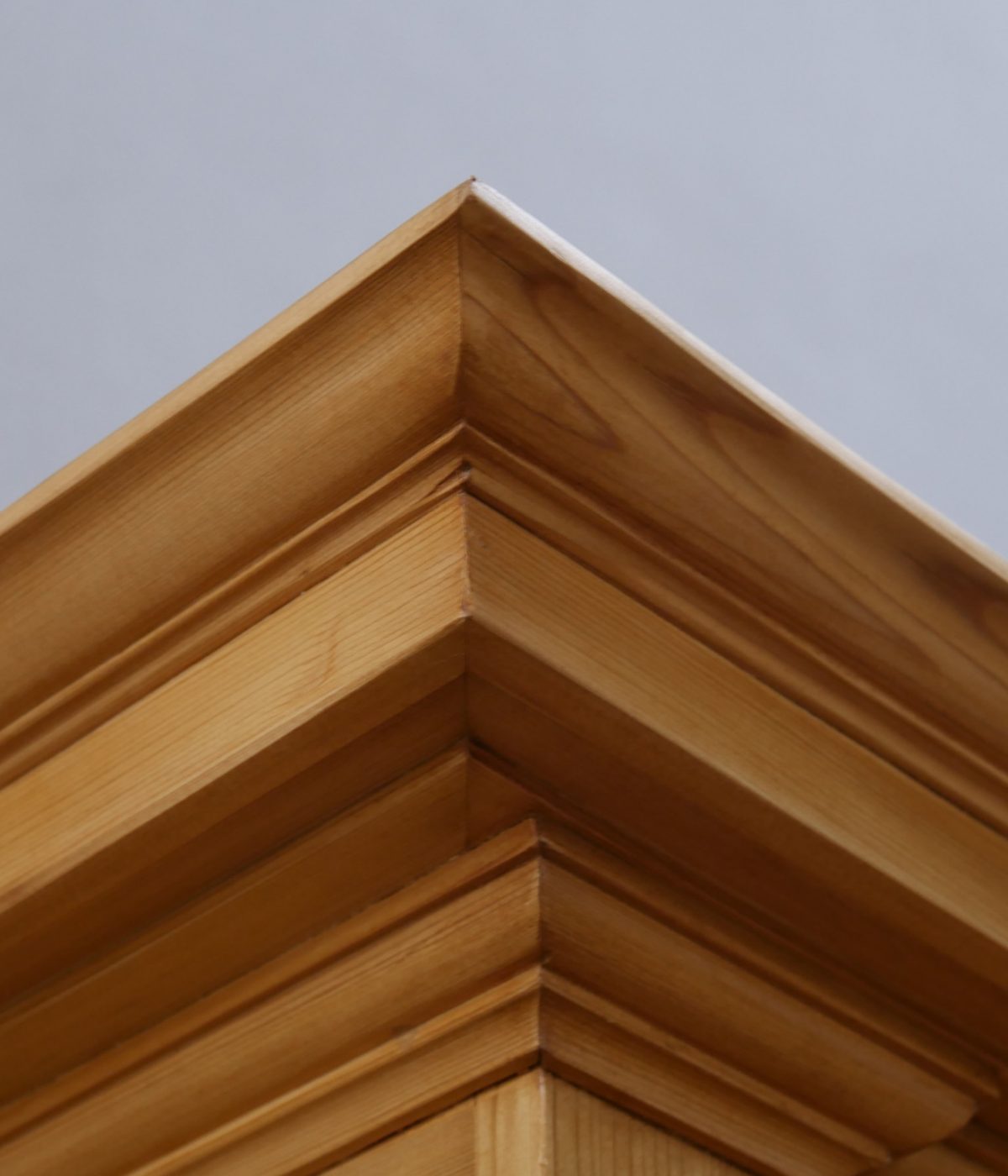 Detailaufnahme der mehrfach getreppten Kranzleiste an einer Schrankecke. Die aufwendige Profilierung und die natürliche Holzmaserung zeigen die exzellente Schreinerarbeit der Gründerzeit.
