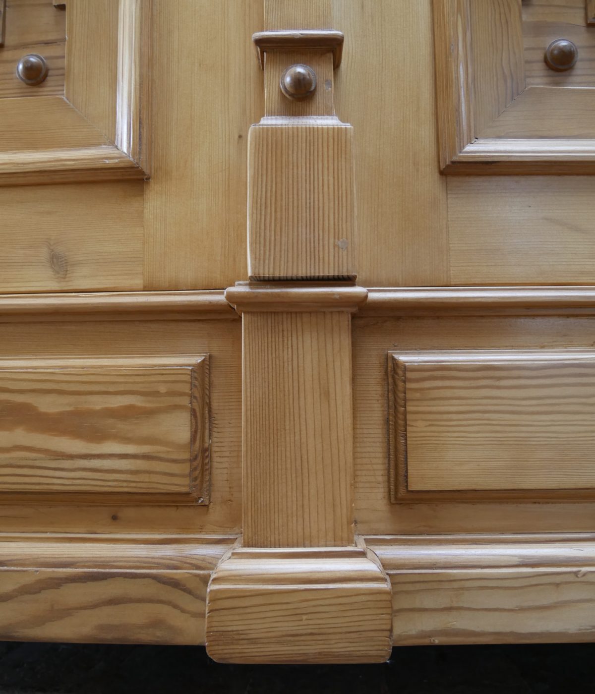 Nahaufnahme eines profilierten Rahmen- und Gesimselements am Schrank. Sichtbar sind die präzise ausgeführten Übergänge sowie die sorgfältige handwerkliche Verarbeitung des Weichholzes.