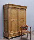 Originaler Gründerzeit Kleider- und Wäscheschrank aus Weichholz von etwa 1880 in restauriertem Zustand. Die große Frontansicht zeigt den zweitürigen Schrank mit aufwendig verzierten Füllungen, breiter Kranzleiste, massivem Sockel und eleganten Kugelfüßen.