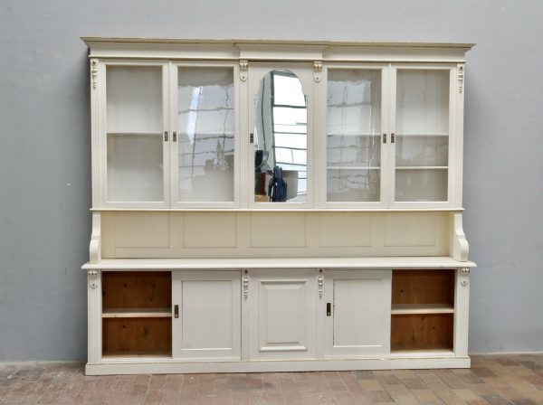 Vorderansicht des vollständig aufgebauten Ladenschranks mit geschlossenen Türen und zum Teil geöffneten Schiebetüren. Die geringe Tiefe des Möbels sowie seine elegante Wirkung sind gut erkennbar.
