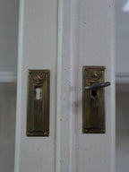 Detailaufnahme der originalen Türbeschläge und Schlüsselschilder mit schöner Alters-Patina. Die historischen Metallbeschläge unterstreichen den authentischen Charakter des Schranks.