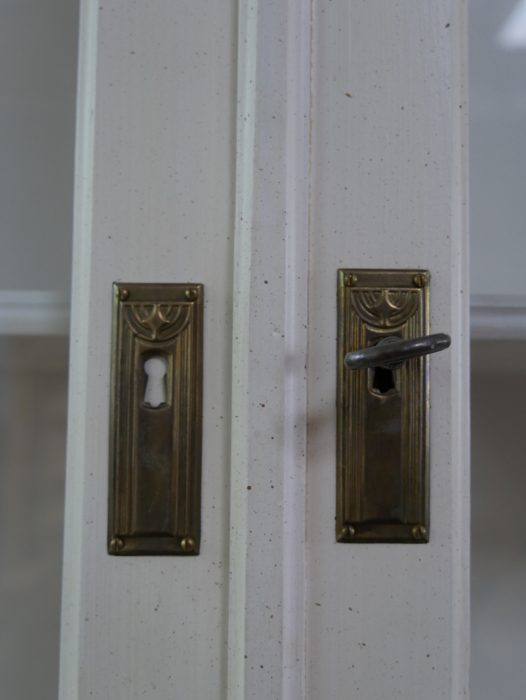 Detailaufnahme der originalen Türbeschläge und Schlüsselschilder mit schöner Alters-Patina. Die historischen Metallbeschläge unterstreichen den authentischen Charakter des Schranks.