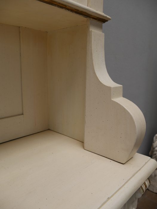 Detailaufnahme der geschweiften seitlichen Regalstütze im Oberteil. Das elegant ausgearbeitete Holzelement verbindet Stabilität mit typischer Gründerzeit-Ornamentik.